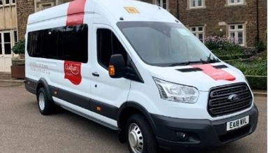 White Ford van with red medical cross markings parked outside a building.