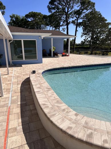 Poolside area with clear water and paved patio.