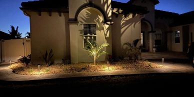 House exterior lit at night with landscaping lights.