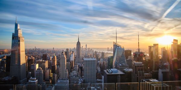 Sunset over a bustling city skyline with iconic skyscrapers.