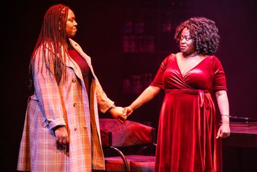 Two women holding hands on stage, expressing emotion.