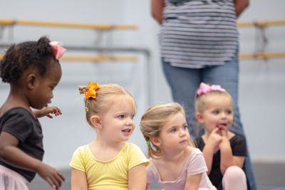 Four young girls in a dance class with an instructor.