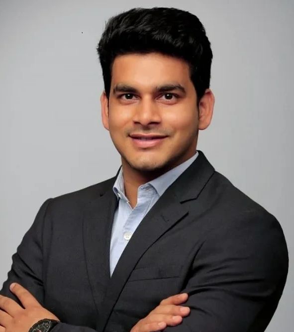 Confident man in a dark suit smiling with arms crossed.