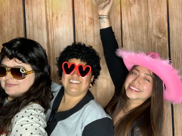 people smiling having fun with props in hand enjoing the photobooth