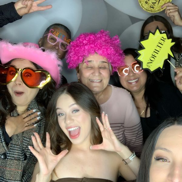 people smiling having fun with props in hand enjoing the photobooth