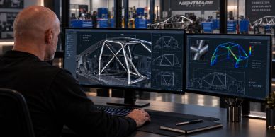 Man working on race car frame design on dual monitors.