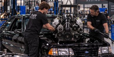 Two mechanics working on a car engine in a workshop.