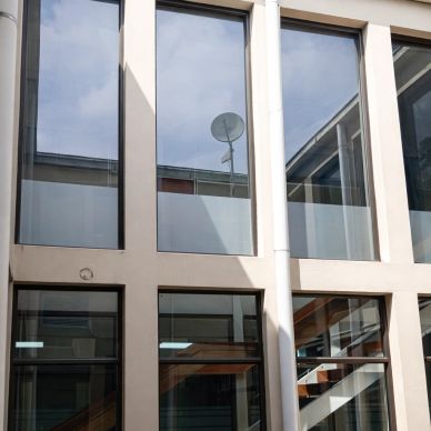 Modern building windows reflecting a satellite dish.