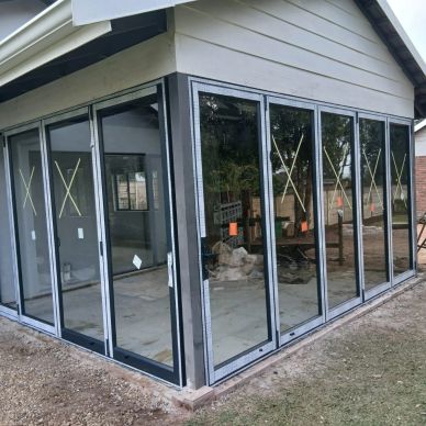 Newly installed glass foldable doors on a modern house corner.
