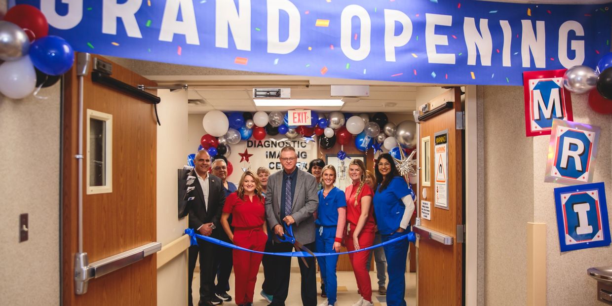 Grand-Opening banner with staff standing about to cut a ribbon.