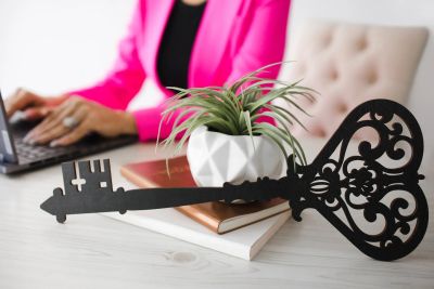 Decorative key on desk with a woman typing in background.