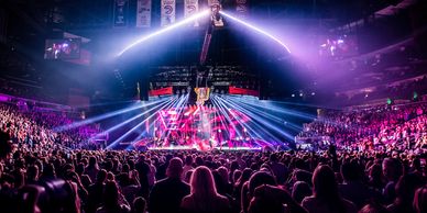 A vibrant concert with colorful lighting and a large crowd in an indoor arena.