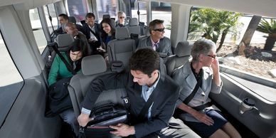 Businesspeople commuting together in a shuttle bus, engaged in various activities.