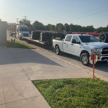 Flatbed truck loaded with industrial cables and a white pickup truck.