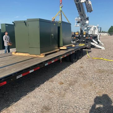 Green industrial cabinets being loaded onto a truck.