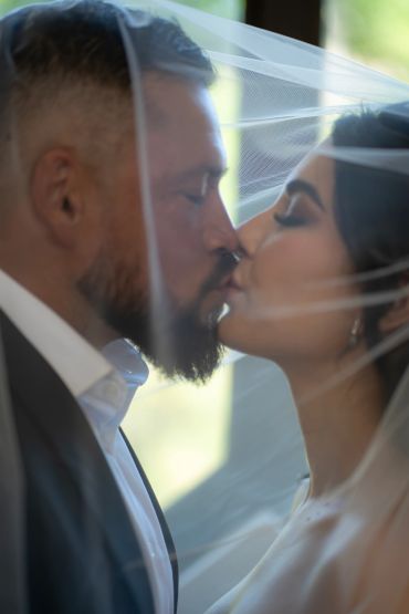 Bride and groom kissing under veil.