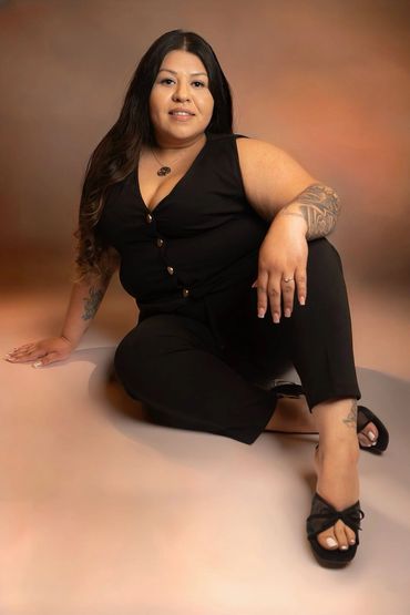 Woman in black outfit posing on floor.
