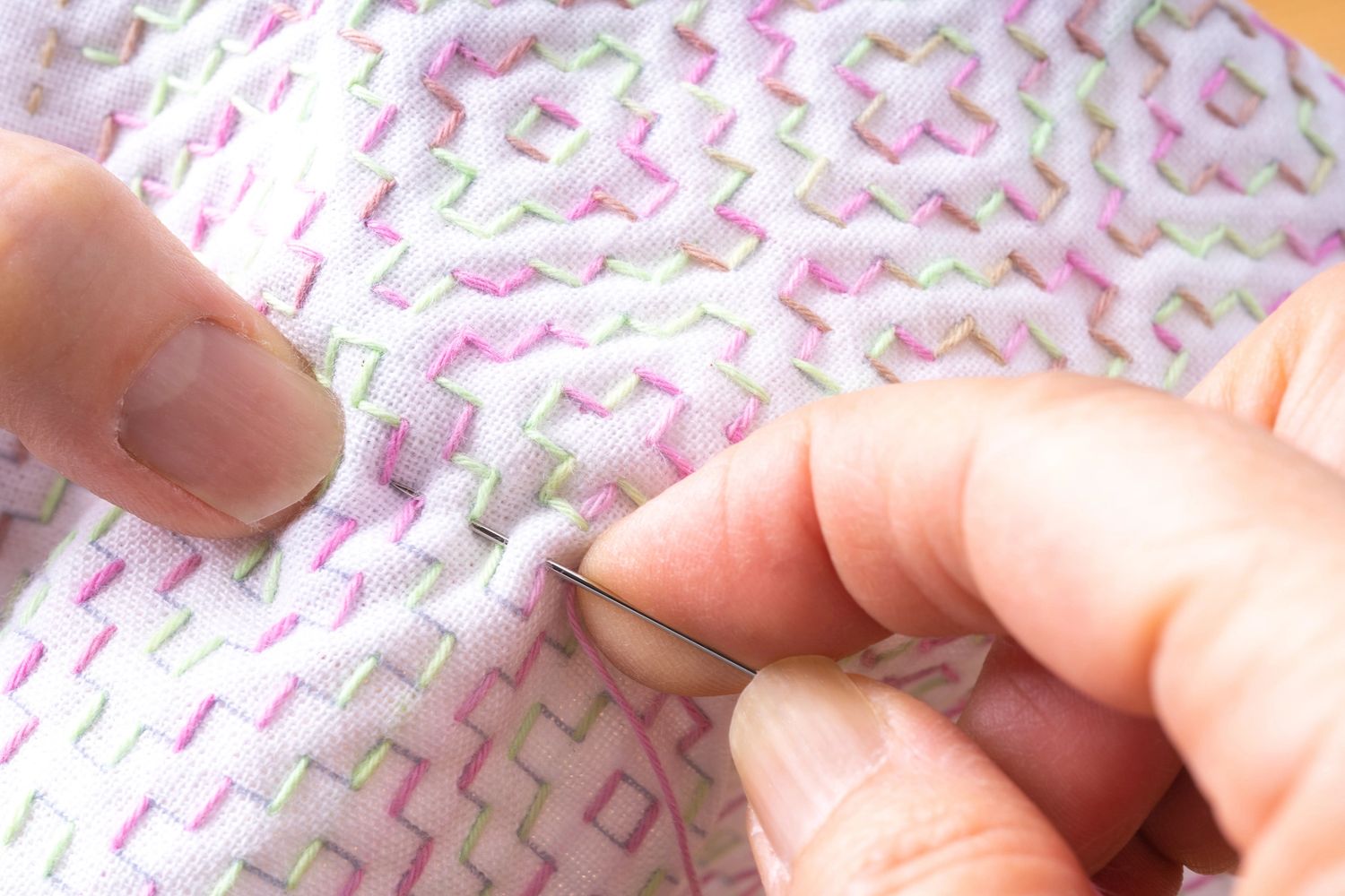 Close-up of hands stitching colorful embroidery on fabric.