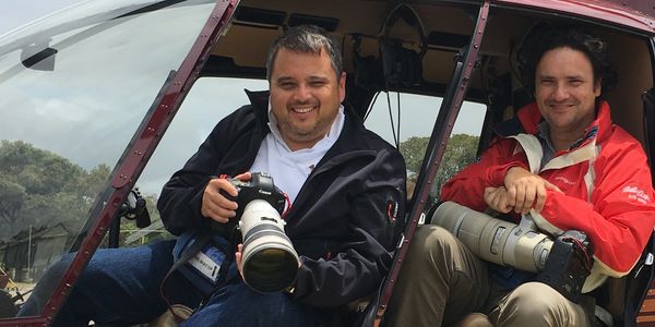 Andrew Parsons and another photographer posing with cameras in a helicopter.
