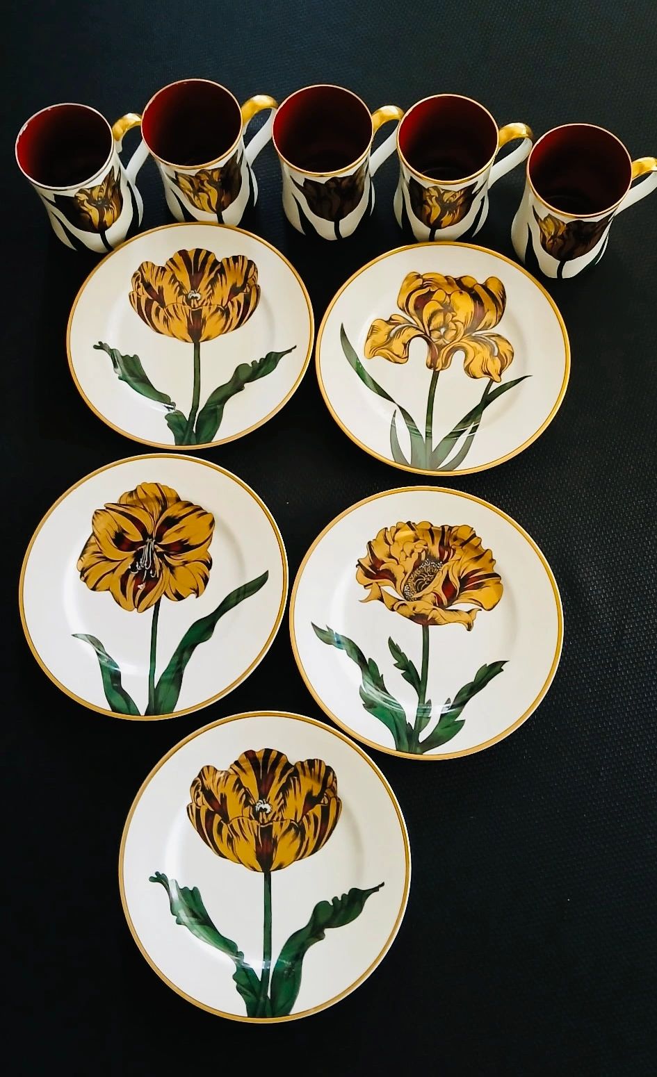 Floral-patterned cups and plates set on a black surface.