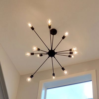 Modern Light Fixture on ceiling next to window.  Fixture has 12 bulbs that radiate from sphere.