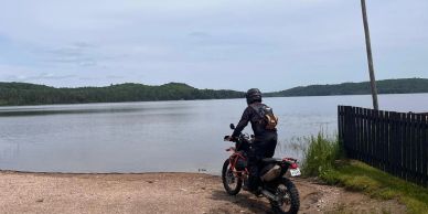 Person on motorcycle by a lakeside.