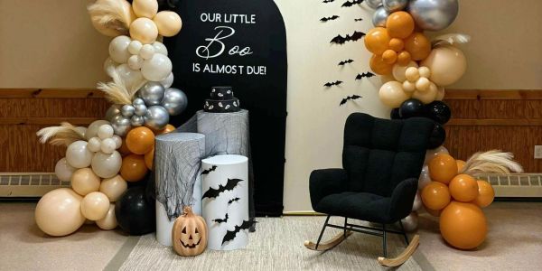 Halloween-themed baby shower setup with balloons and bat decor.