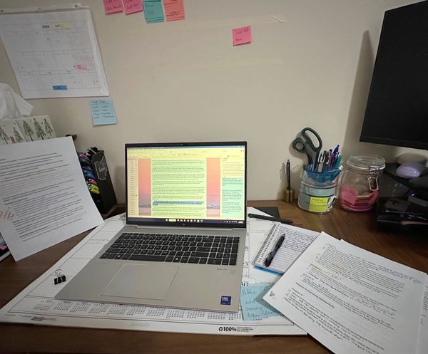 Desk covered in paperwork with a laptop open