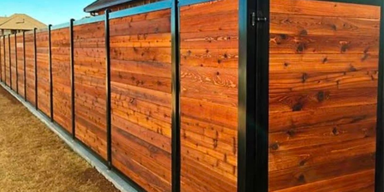 A wooden privacy fence with black metal posts enclosing a yard.