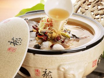 Traditional Chinese clay pot with soup being poured in.