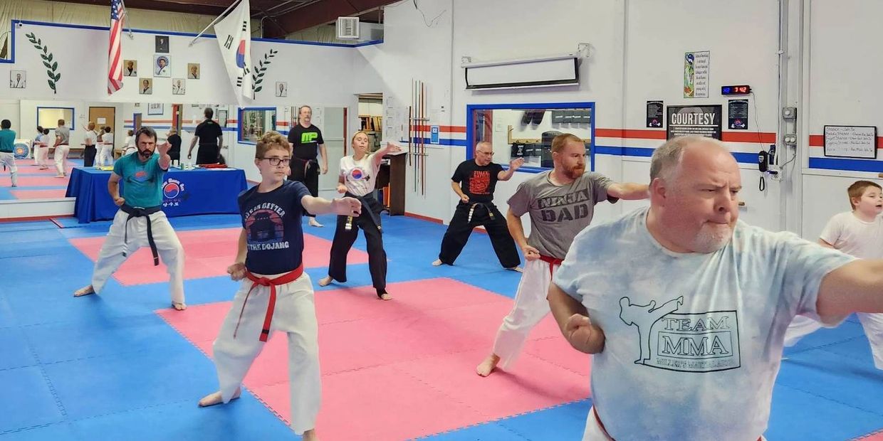 Adults practicing martial arts in a focused training session.
