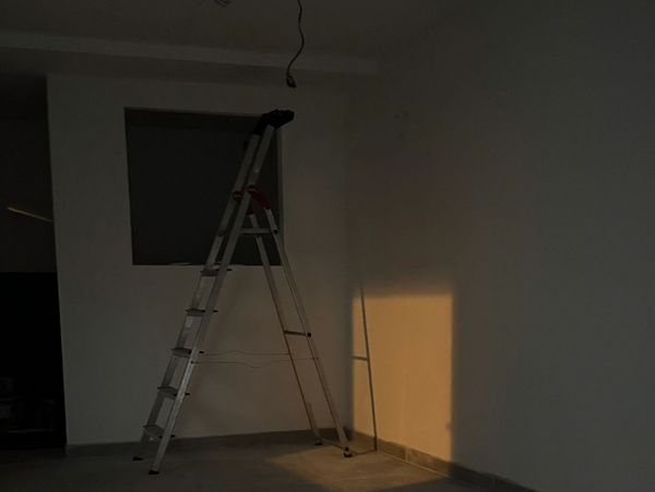 Leiter in leerem Raum mit Schatten an der Wand.