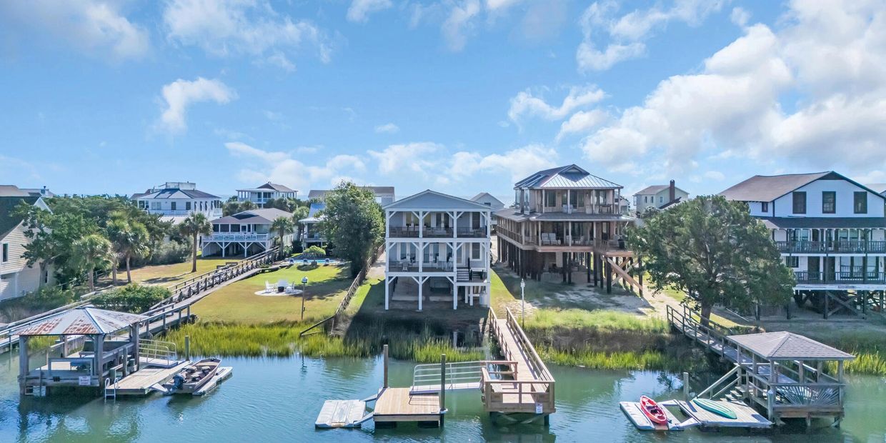 Waterfront houses with docks and boats under a partly cloudy sky.
