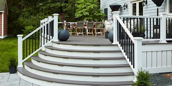 Curved outdoor stairs leading to a wooden deck with black and white railing.