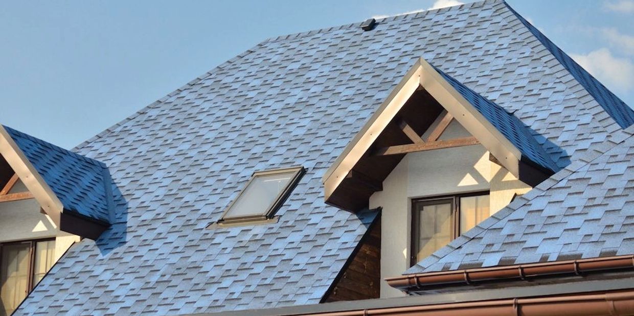 Blue shingled roof with skylight and dormer windows on a house.