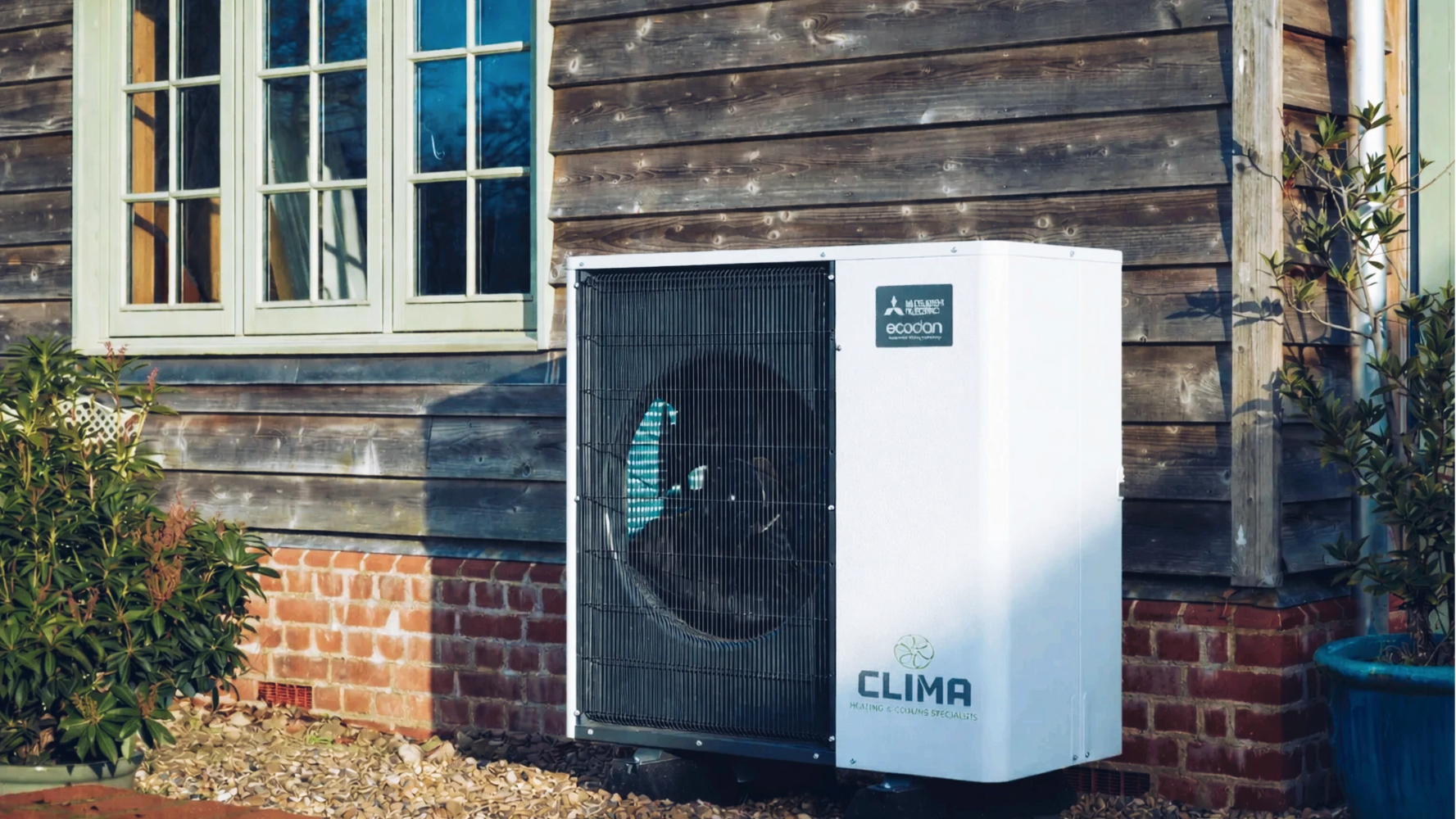 A Mitsubishi Electric Ecodan heat pump installed outside a wooden house.