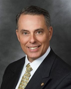 Professional headshot of a man in a suit.
