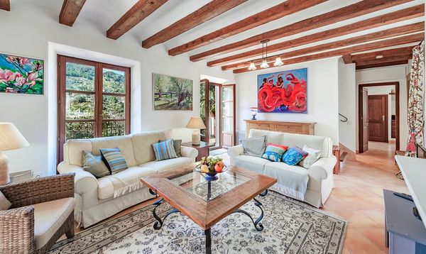 Cozy living room with wooden beams, two white sofas, and vibrant artwork on the walls.
