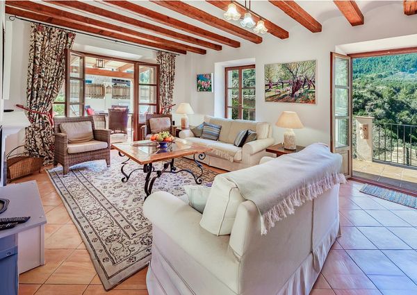 Cozy living room with wooden beams, comfortable sofas, and open doors to a scenic outdoor view.