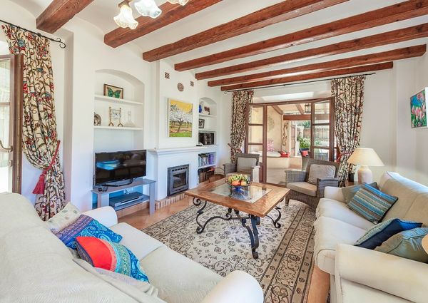 Cozy living room with wooden beams, patterned curtains, and comfortable sofas around a decorative coffee table.