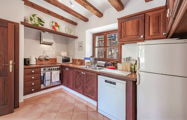Cozy kitchen with wooden beams, cabinets, and modern appliances.