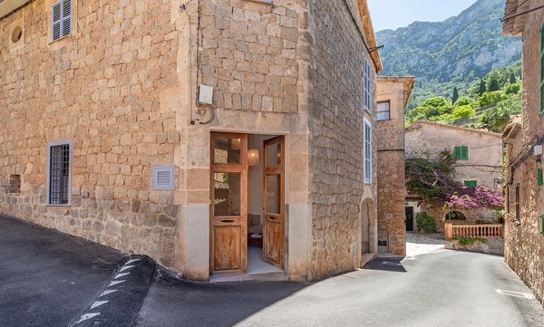 Stone building with wooden door on a quiet street in a mountainous village.