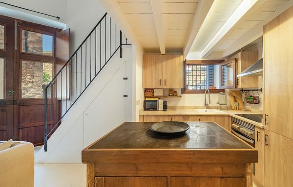 Cozy kitchen with wooden cabinetry and island under a white ceiling with beams.