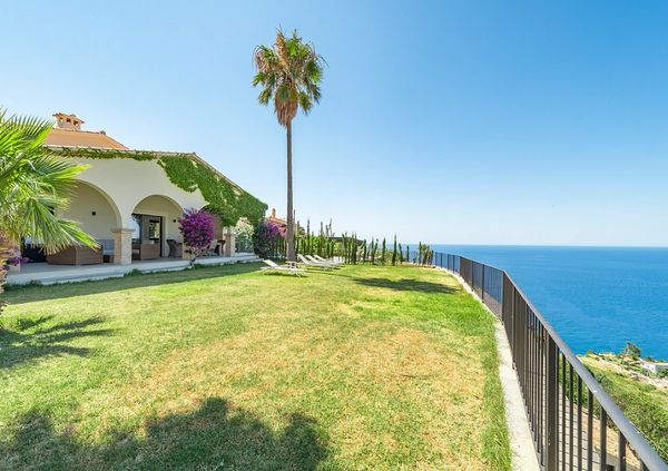 Coastal house with green lawn and ocean view.
