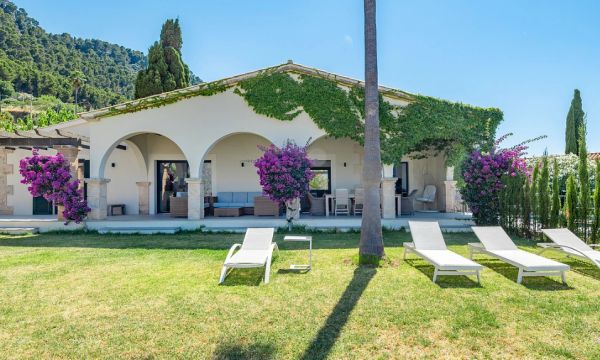 White house with arches and garden lounge chairs.