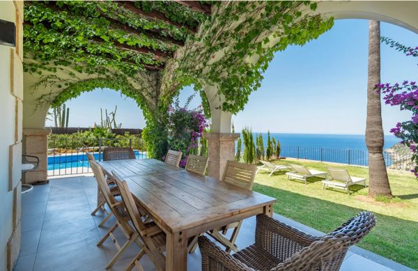 Outdoor dining area with ocean view and lounge chairs.