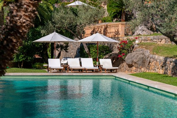 Empty poolside lounge chairs with white umbrellas.