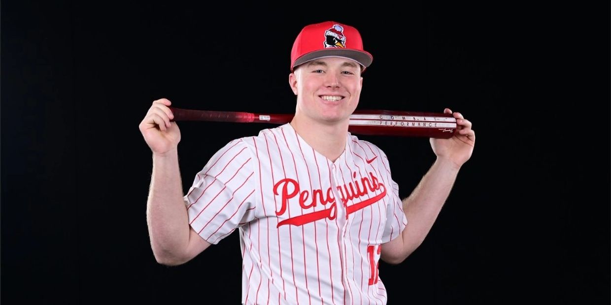 Baseball player smiling with bat on shoulders.