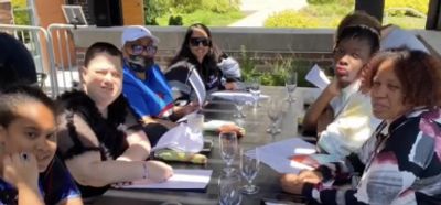 A group of people sitting around an outdoor table with menus and glasses.