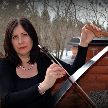 Woman playing a string instrument bow outdoors in winter.